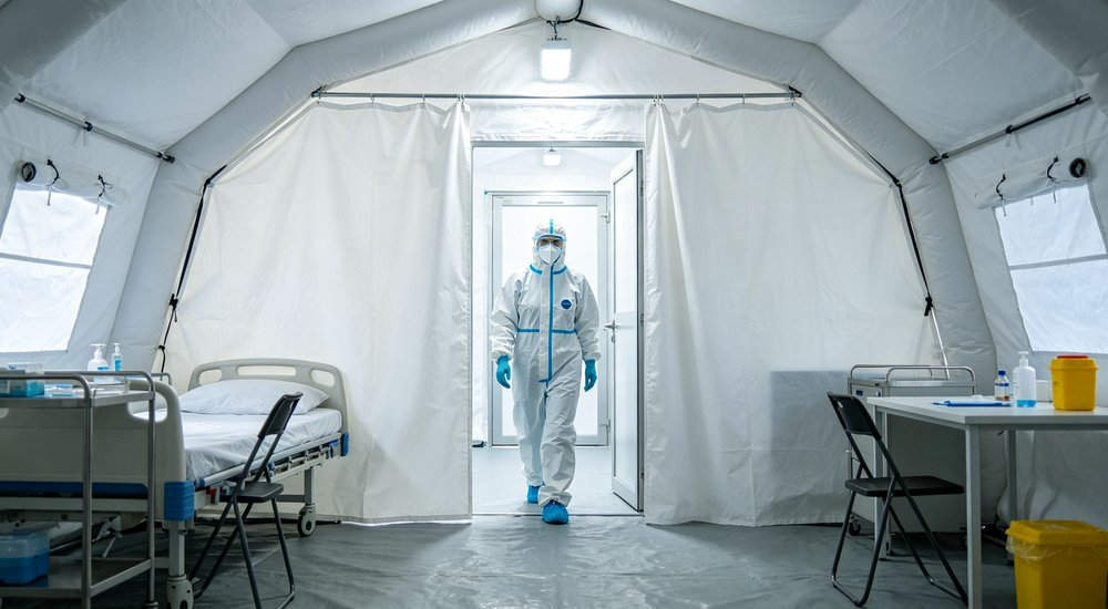 Anteroom buffer zone inside inflatable isolation tent, transition area with PPE, bright interior red and white inflatable emergency shelter for disaster relief operations