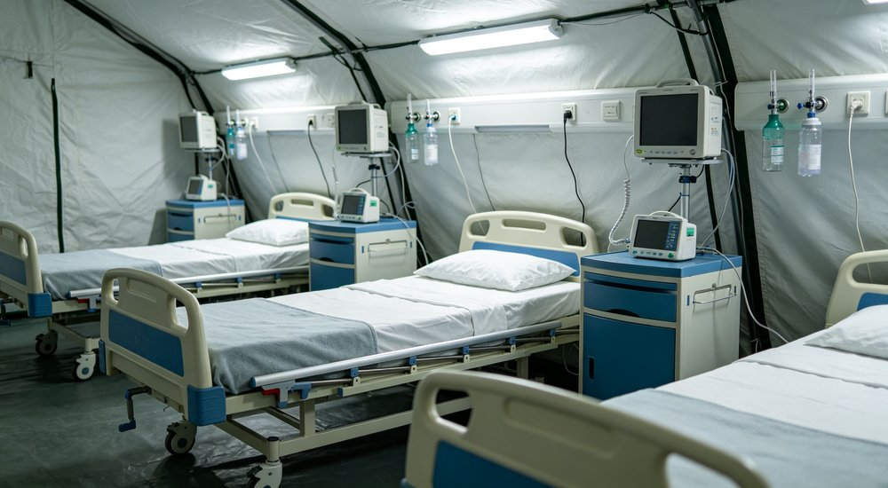 Bed area inside inflatable medical tent with patient beds, bright lighting red and white inflatable emergency shelter for disaster relief operations