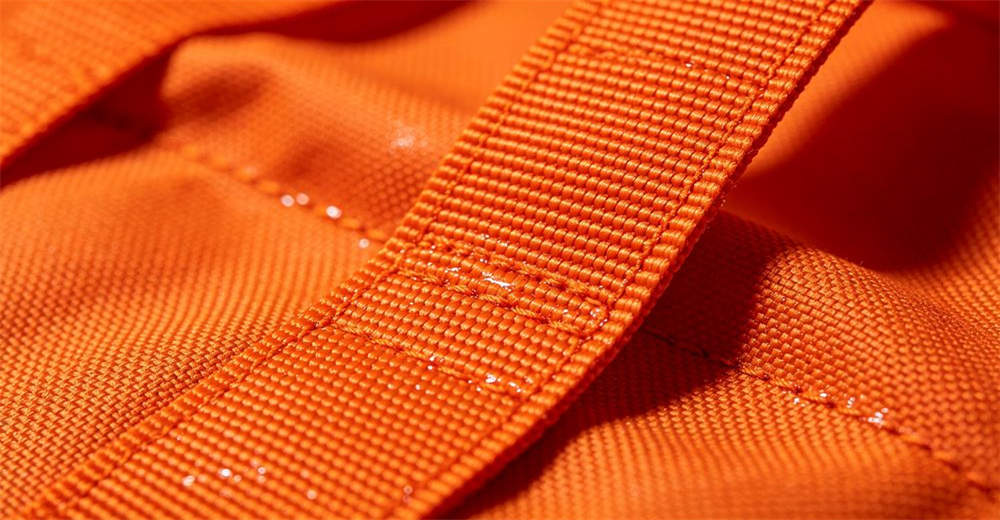 Macro close-up of CORDURA waterproof fabric texture on orange rescue throw bag body showing durable abrasion-resistant weave for reliable water rescue operations and emergency response