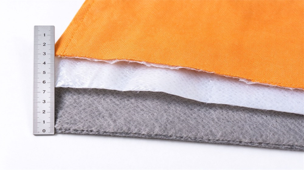 Macro studio shot of firefighter turnout gear three layer cross section showing outer shell moisture barrier and thermal liner separated into three swatches on light gray background