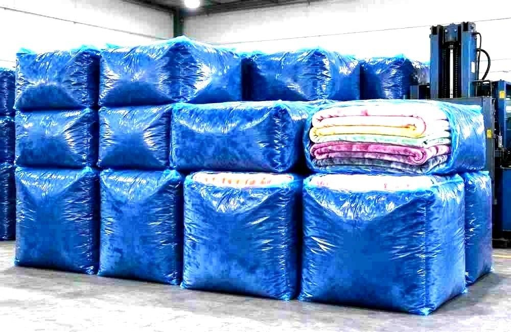 Compressed blanket bales on pallets ready for camp dispatch and freight, showing durable blankets camp washing and packing for relief logistics
